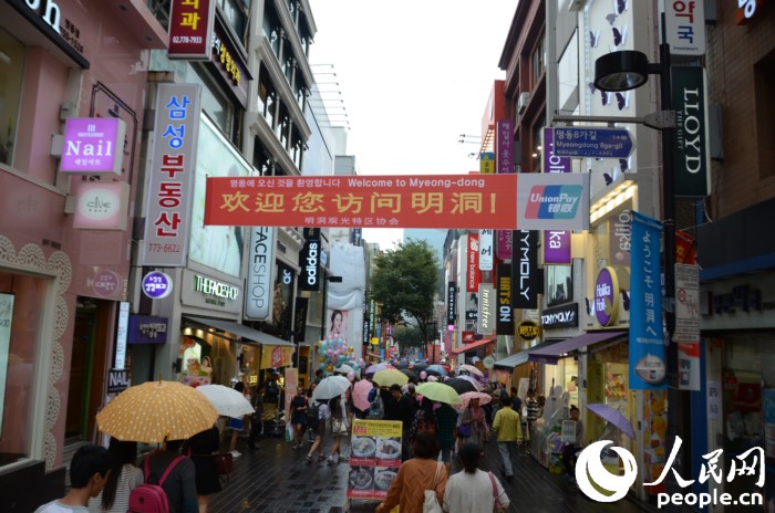 國(guó)慶黃金周期間，冒雨在明洞街頭購(gòu)物的中國(guó)游客們。（攝影：裴埈基）